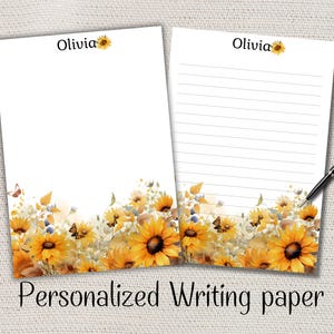 Peut inclure: Deux feuilles de papier à lettres personnalisées avec un motif de tournesol. Le haut de chaque feuille porte le nom "Olivia" et un graphisme de tournesol. Le bas du papier présente une bordure florale à l'aquarelle avec des tournesols et des papillons. Un stylo repose sur la feuille lignée.