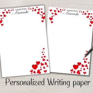 Peut inclure: Deux feuilles de papier à lettres blanches personnalisées avec des cœurs rouges. Le texte "a note from Amanda" est imprimé en haut. La phrase "Personalized Writing paper" est imprimée en bas.