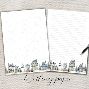 Könnte beinhalten: Zwei Blatt weißes Briefpapier mit einer Aquarellillustration eines winterlichen Dorfes am unteren Rand und blauen Schneeflocken im Hintergrund. Ein Blatt ist leer, das andere hat horizontale Linien und einen schwarzen Stift.