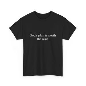 May include: Black t-shirt with the white text "God's plan is worth the wait." The shirt has a crew neck and short sleeves. The fabric appears to be a soft, comfortable material.
