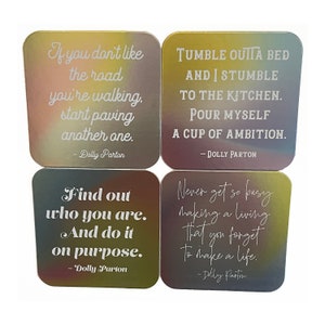 May include: Four colorful coasters with inspirational quotes by Dolly Parton. Each coaster features a different quote and a gradient background. The quotes are: "If you don't like the road you're walking, start paving another one.", "Tumble outta bed and I stumble to the kitchen. Pour myself a cup of ambition.", "Find out who you are. And do it on purpose.", and "Never get so busy making a living that you forget to make a life."