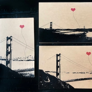 May include: Three black and white illustrations of the Golden Gate Bridge with a red heart balloon floating above each bridge.