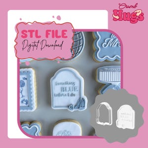 May include: A collection of light blue and white decorated cookies featuring various shapes including a tombstone design with the text Something BLUE I do, alongside two white plastic cookie cutters, one of which matches the tombstone shape.