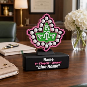 May include: A decorative desk plaque featuring a pink and green ivy leaf emblem with white circular accents. The black base displays the text Name, # - Chapter - Crossed, and Line Name in white and pink lettering on a solid black rectangular stand.
