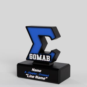 May include: A black and blue trophy with the text "GOMAB" and other text. The trophy has a blue letter "C" shape with a black outline, mounted on a black base. The base has text that reads "Name # - Chapter - Crossed "Line Name".