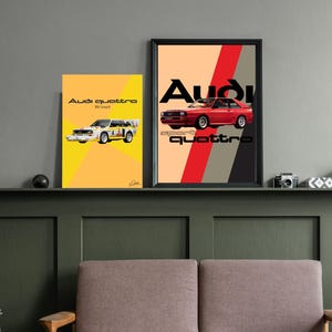 May include: Two framed Audi Quattro car posters. One poster features a red car with the word "Audi" in black and "sport quattro" in white. The other poster has a yellow background with a white car and the words "Audi quattro".