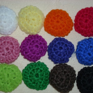 May include: Twelve crocheted round hair scrunchies in various colors, including white, yellow, orange, pink, purple, blue, green, brown, and black.