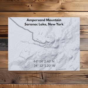 Può includere: Una mappa topografica di Ampersand Mountain a Saranac Lake, New York, con curve di livello e indicazioni di altitudine. La mappa include il nome della montagna, la sua posizione e le coordinate: 44° 14' 2.40" N, -74° 12' 1.20" W. L'altitudine della montagna è di 1022 m.