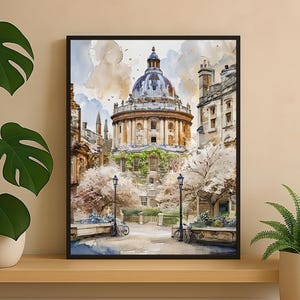 Puede incluir: Pintura a la acuarela de un edificio abovedado con arquitectura circundante, enmarcada en negro. La obra representa una escena callejera con bicicletas, farolas y árboles en flor. La paleta de colores incluye azules suaves, beige y verdes.