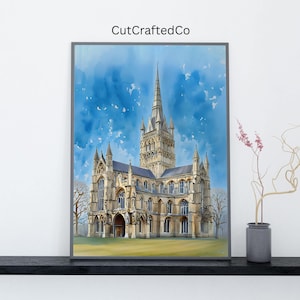 May include: Framed watercolor print of a cathedral with a tall spire, set against a blue sky. The artwork features detailed architectural elements and is labeled "CutCraftedCo" in the upper left corner. The print is displayed on a black shelf.