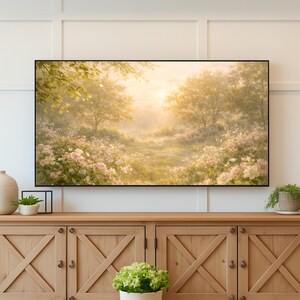 May include: A framed landscape painting depicting a sunlit meadow with trees and flowers. The artwork features a path leading into the distance, surrounded by pink and white blossoms and lush greenery. The painting is displayed above a wooden cabinet.