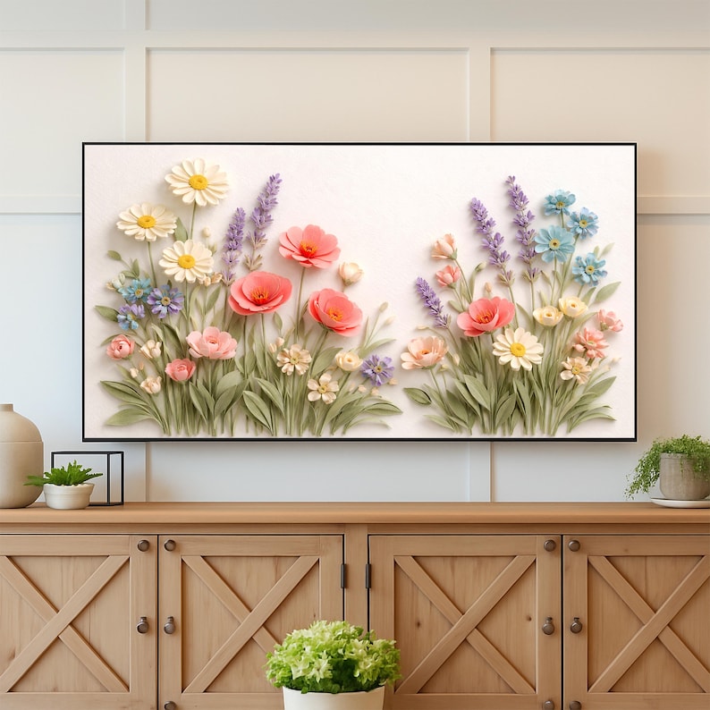May include: A framed floral art piece featuring a variety of colorful flowers. The artwork showcases a 3D effect with daisies, poppies, lavender, and other blooms in shades of pink, yellow, blue, and purple. The piece is set against a white background.