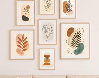 Op de afbeelding: Een verzameling ingelijste kunstafdrukken met abstracte botanische ontwerpen. Elke afdruk heeft een beige achtergrond met aquarel-achtige vormen en lijntekeningen van bladeren en planten in bruin, groen en zwart.