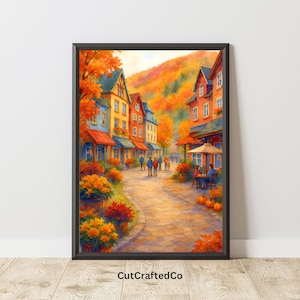 May include: A framed watercolour print depicting a European village street in autumn. The buildings feature red, blue, and yellow facades. The street is lined with orange and red foliage, and people are walking along the cobblestone path. Pumpkins are near a cafe.