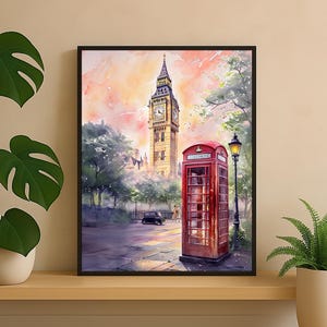 May include: Watercolor painting of London's iconic landmarks, featuring Big Ben and a red telephone box. The artwork captures a street scene with a vintage car, a lamppost, and lush trees, set against a soft, colorful sky. The framed art piece is displayed on a wooden shelf.
