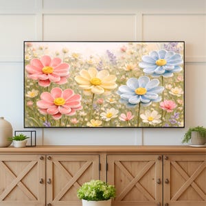 May include: A framed floral art print featuring large, textured flowers in shades of pink, yellow, and blue. The flowers have yellow centers and are set against a backdrop of smaller white and purple flowers, creating a vibrant, colorful scene.