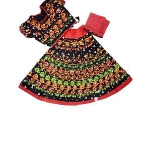 May include: A traditional Indian outfit featuring a black top and skirt, both adorned with colorful embroidery. The skirt has a red border, and a matching red scarf is included. The embroidery includes orange, green, and white floral patterns.