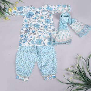 K&ouml;nnte beinhalten: Ein dreiteiliges Baby-Outfit. Das wei&szlig;e Oberteil hat blaue Blumenmuster, die hellblaue Hose ein Zickzack-Design und einen passenden Schal. Das Outfit ist aus weichem Stoff und f&uuml;r Babys geeignet.
