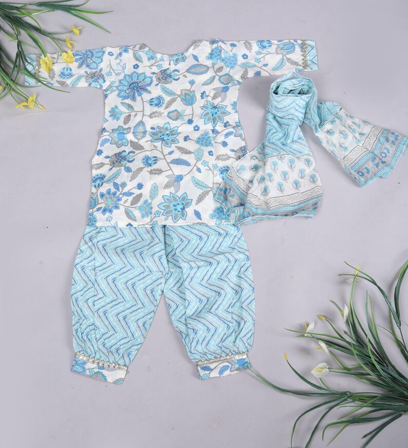 K&ouml;nnte beinhalten: Ein dreiteiliges Baby-Outfit. Das wei&szlig;e Oberteil hat blaue Blumenmuster, die hellblaue Hose ein Zickzack-Design und einen passenden Schal. Das Outfit ist aus weichem Stoff und f&uuml;r Babys geeignet.