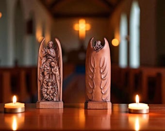 May include: Two wooden angel figurines, one depicting a nativity scene and the other with carved wings. The figurines are brown and stand on a reflective wooden surface. Lit candles flank the figurines, with a church interior in the background.
