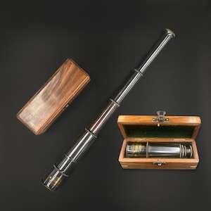 Op de afbeelding: Een vintage messing en houten telescoop met een donkere afwerking, samen met twee houten opbergdozen. Eén doos is open en onthult de compacte vorm van de telescoop. De telescoop is uitgeschoven en toont zijn vele secties.