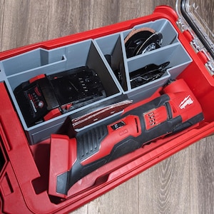 May include: A red and black Milwaukee M12 FUEL oscillating multi-tool with accessories, including a battery, sanding pad, and cutting blades, organized in a red storage case with gray dividers.