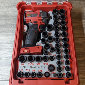 May include: A red impact wrench and socket set in a red case. The set includes a cordless impact wrench, various sockets, and the text "3/8" IMPACT". The case is open, revealing the tools neatly arranged.