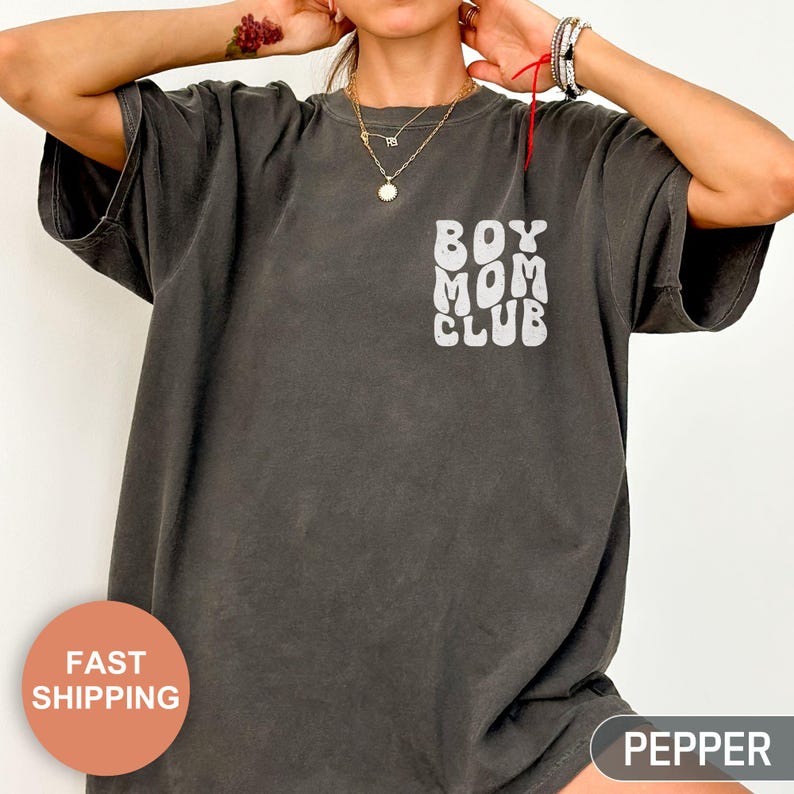以下が含まれることがあります： 「BOY MOM CLUB」の白文字がプリントされた濃いグレーのTシャツ。半袖でゆったりとしたシルエットです。柔らかく着心地の良い素材を使用しています。カジュアルウェアです。
