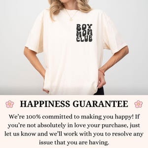 以下が含まれることがあります： 黒い丸みを帯びたフォントで「BOY MOM CLUB」というテキストが入ったクリーム色のTシャツ。Tシャツは人が着ています。Tシャツは半袖でゆったりとしたフィット感です。