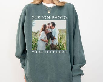 May include: Blue spruce-colored sweatshirt with a custom photo and text. The photo shows a family of three. The text on the sweatshirt reads "CUSTOM PHOTO" above the photo and "YOUR TEXT HERE" below it. The words "BLUE SPRUCE" are at the bottom.