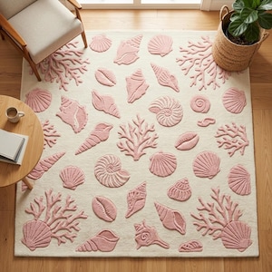 May include: A rectangular off-white rug with a pattern of pink seashells and coral. The rug features various seashell shapes and coral branches in a raised, textured design. The rug is placed on a wooden floor.