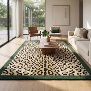 May include: A rectangular area rug featuring a prominent leopard print pattern in shades of tan, brown, and black, framed by a solid dark green border. The rug is positioned on a light-colored wooden floor, showcasing a repeating animal-inspired design.