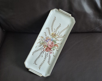 May include: A rectangular, off-white serving tray with a floral bouquet design in the center. The bouquet features pink, red, yellow, and blue flowers. Gold accents frame the tray and adorn the sides.