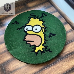 May include: A circular green rug with a cartoon depiction of Homer Simpson. The rug features a yellow Homer Simpson design with black outlines against a green backdrop. The rug is placed on a wooden floor.