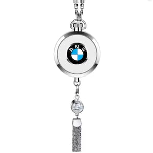 Op de afbeelding: Een zilveren auto-hanger met een witte, ronde hanger met het BMW-logo. De hanger heeft een bungelend kristal en een zilveren kwast. Het BMW-logo is zwart, wit en blauw.