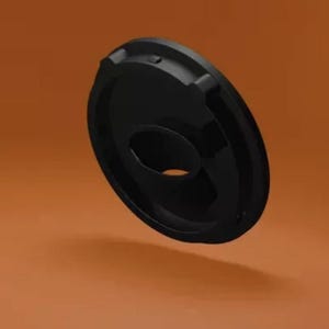 May include: A black, circular object with a central hole and raised edges. The object appears to be made of a smooth, glossy material. The design includes three small, evenly spaced protrusions on the outer rim.