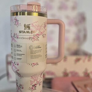 May include: A white ceramic mug with a black handle and the text "But First, Coffee" in a bold, black font. The mug is set against a blurred background, suggesting a cozy setting.