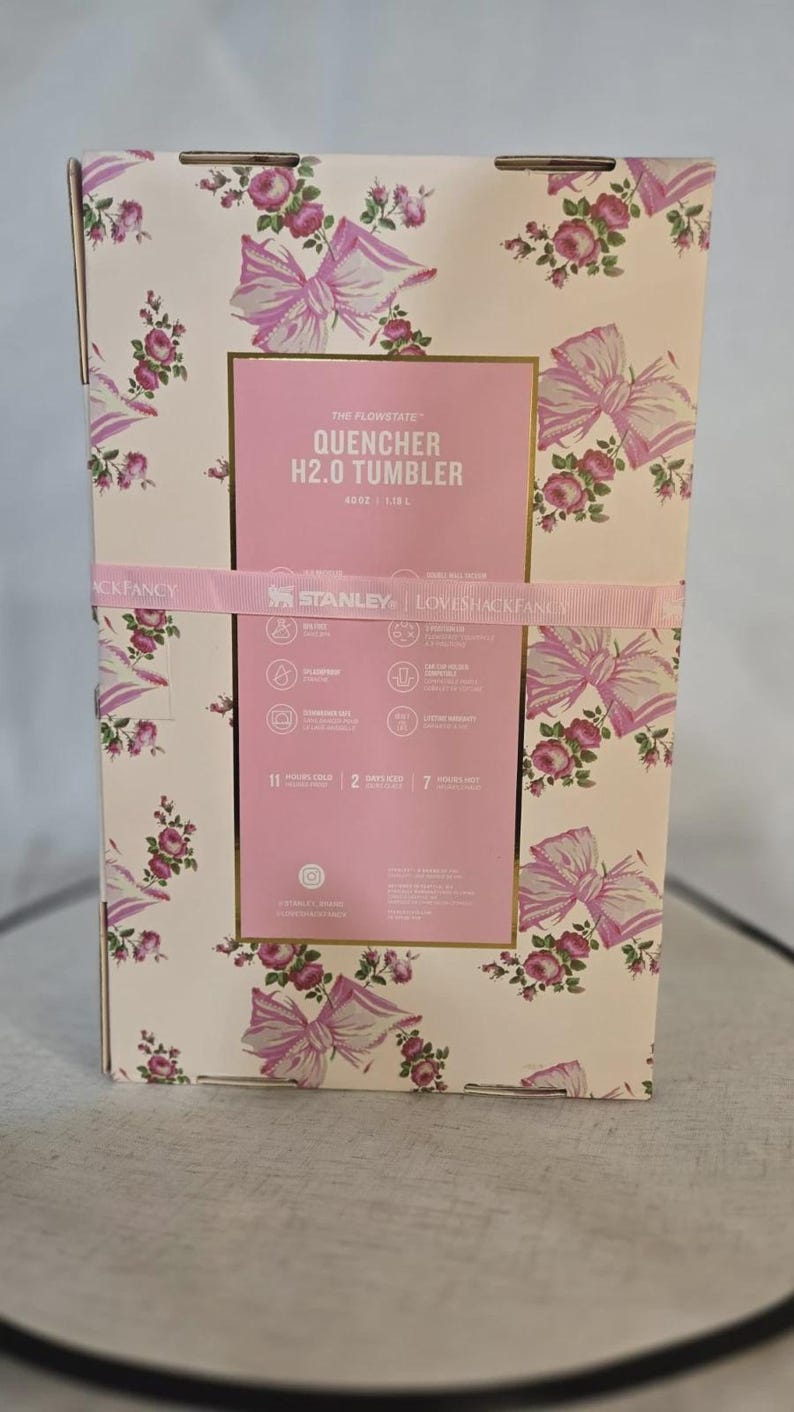 May include: A white ceramic mug with a black handle and the text "But First, Coffee" in a bold, black font. The mug is set against a blurred background, suggesting a cozy setting.