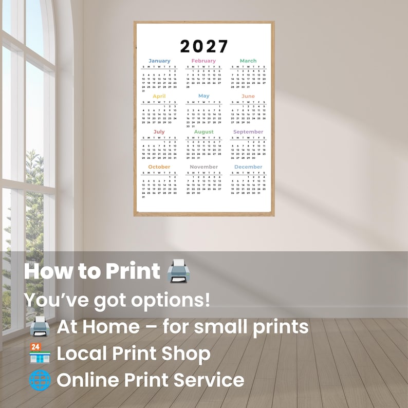 May include: A wall-mounted 2027 calendar print featuring twelve months arranged in a grid. Each month name is displayed in a different color above its respective grid of dates. The calendar is enclosed in a light-colored wooden frame.