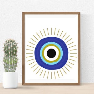 May include: A framed print featuring a stylized eye design. The eye is composed of concentric circles in blue, gold, and black, surrounded by gold rays. A cactus in a white pot is to the left of the framed art.