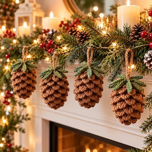 May include: Four crocheted pinecone ornaments hanging in a row. Each ornament features a textured brown body with a green crocheted top and a small jute loop for hanging. The pinecones are crafted with detailed, layered stitches.