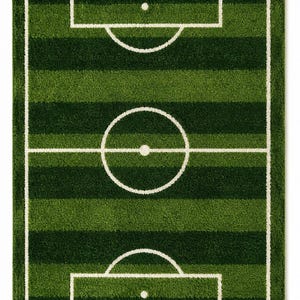 Puede incluir: Una alfombra rectangular con un diseño de campo de fútbol verde con rayas horizontales alternas en verde claro y oscuro. La alfombra incluye líneas blancas que representan el círculo central, las áreas de penalti, las áreas de meta y los córneres.