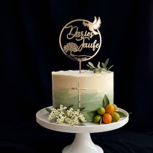 Tauftorte in Weiß und Grün mit rundem goldenem Cake Topper „Zur Taufe“, Taubenmotiv und floralen Details. Ein goldenes Kreuz schmückt die Tortenseite.