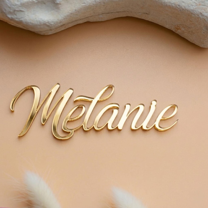 Personalisierter Namensschriftzug „Melanie“ aus goldfarbenem Spiegelacryl als Tortendeko zur Erstkommunion für Mädchen und Jungen.