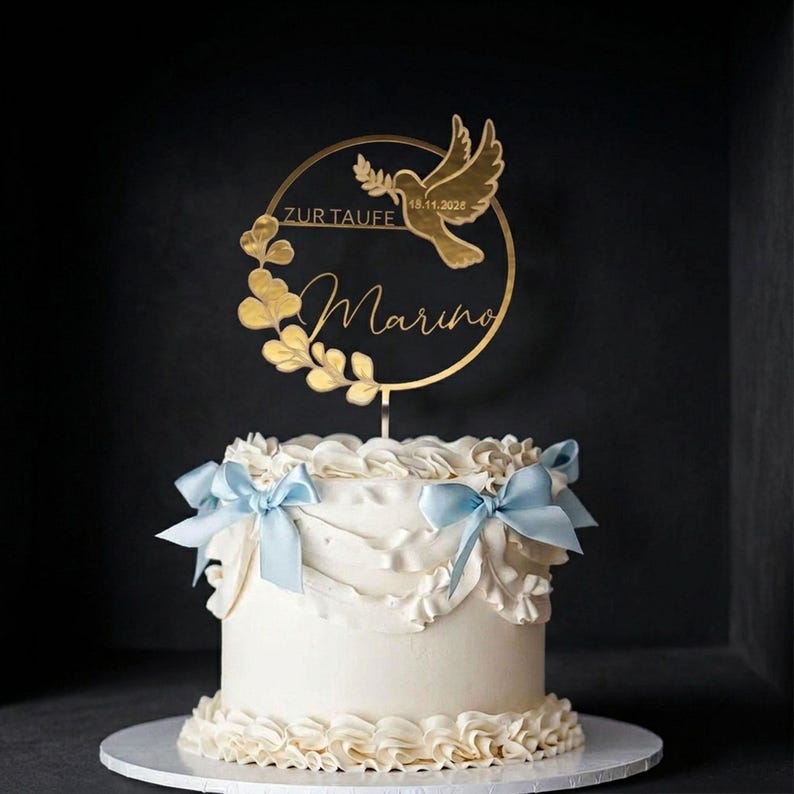 Cake Topper Taufe personalisiert Gold mit Namen „Marius“, Taube und Eukalyptuskranz auf einer weißen Tauftorte mit hellblauen Schleifen – Taufe Deko Torte Junge.