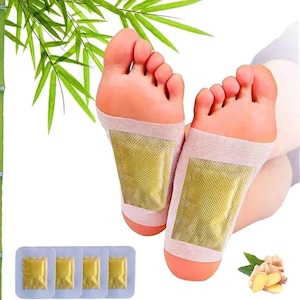 May include: Image of feet with foot pads applied. The pads are rectangular with a gold-colored center and a pinkish-white border. Several individual pads are also shown. Bamboo leaves and ginger are in the background.