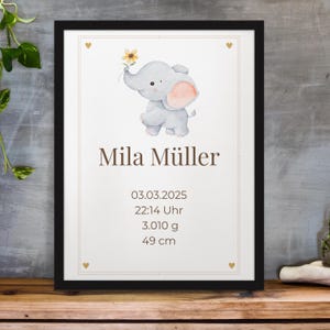 May include: Framed print featuring a watercolor illustration of a gray elephant holding a yellow flower. The name "Mila Müller" is displayed in brown text, along with the date, time, weight (3.010 g), and height (49 cm).