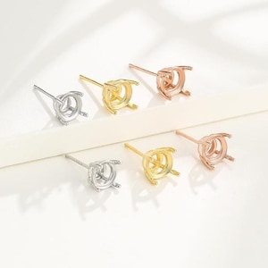 Puede incluir: Seis pendientes de botón en tonos plata, oro y oro rosa. Cada pendiente tiene un engaste redondo para una piedra preciosa. Los pendientes se muestran sobre una superficie blanca, resaltando sus diferentes colores y diseños.