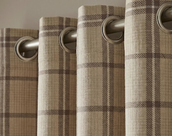 May include: Close-up of beige and brown plaid curtains with silver grommets. The curtains have a classic check pattern in shades of beige and brown. The grommets are made of metal and are evenly spaced along the top of the curtains.
