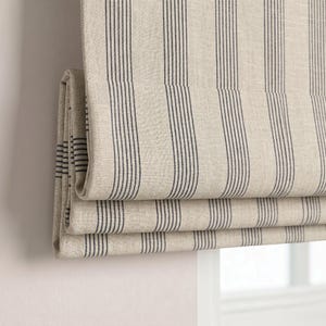 Könnte beinhalten: Beige und marineblau gestreifter römischer Rollo. Der Stoff ist in horizontalen Schichten gefaltet, wodurch die innere Struktur sichtbar wird. Die Streifen sind vertikal und gleichmäßig angeordnet, was ein klassisches, neutrales Design ergibt. Der Rollo bedeckt teilweise ein Fenster.